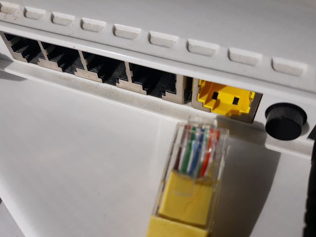 An Ethernet cable being plugged into the WAN port of a router