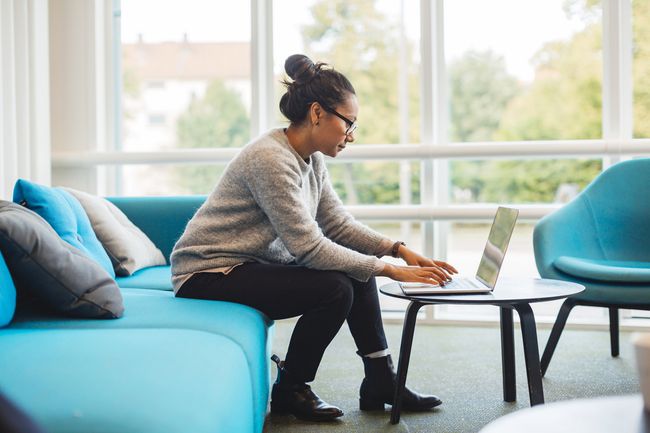 Woman using laptop computer in living room at home