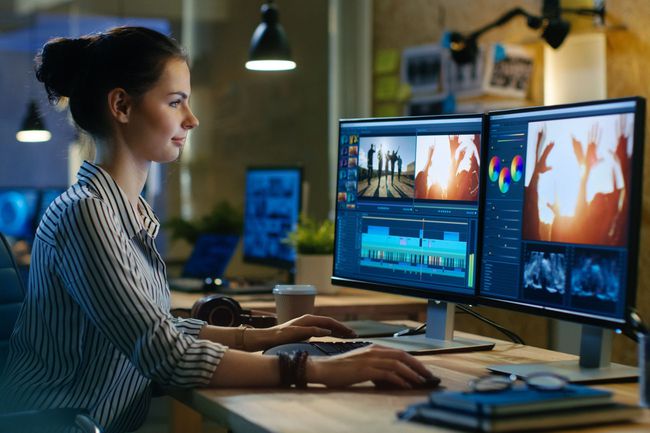 woman editing video on a computer with 2 screens