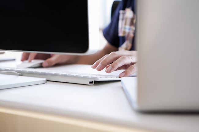 A woman sitting in front of her computer typing using a keyboard.