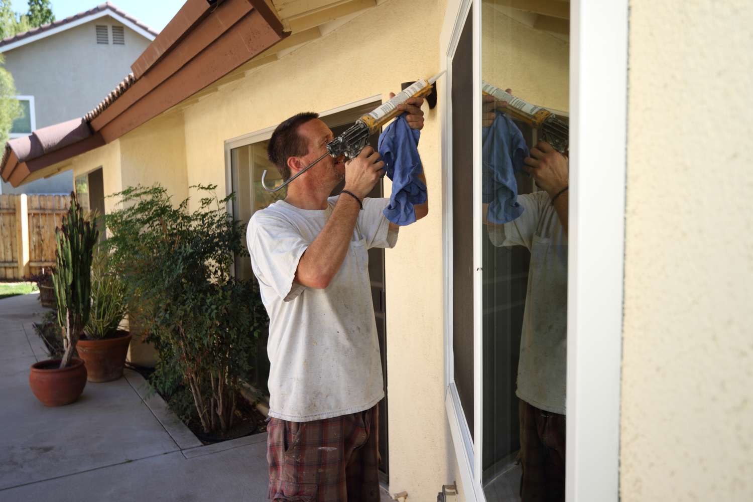 Homeowner using a caulking gun outside